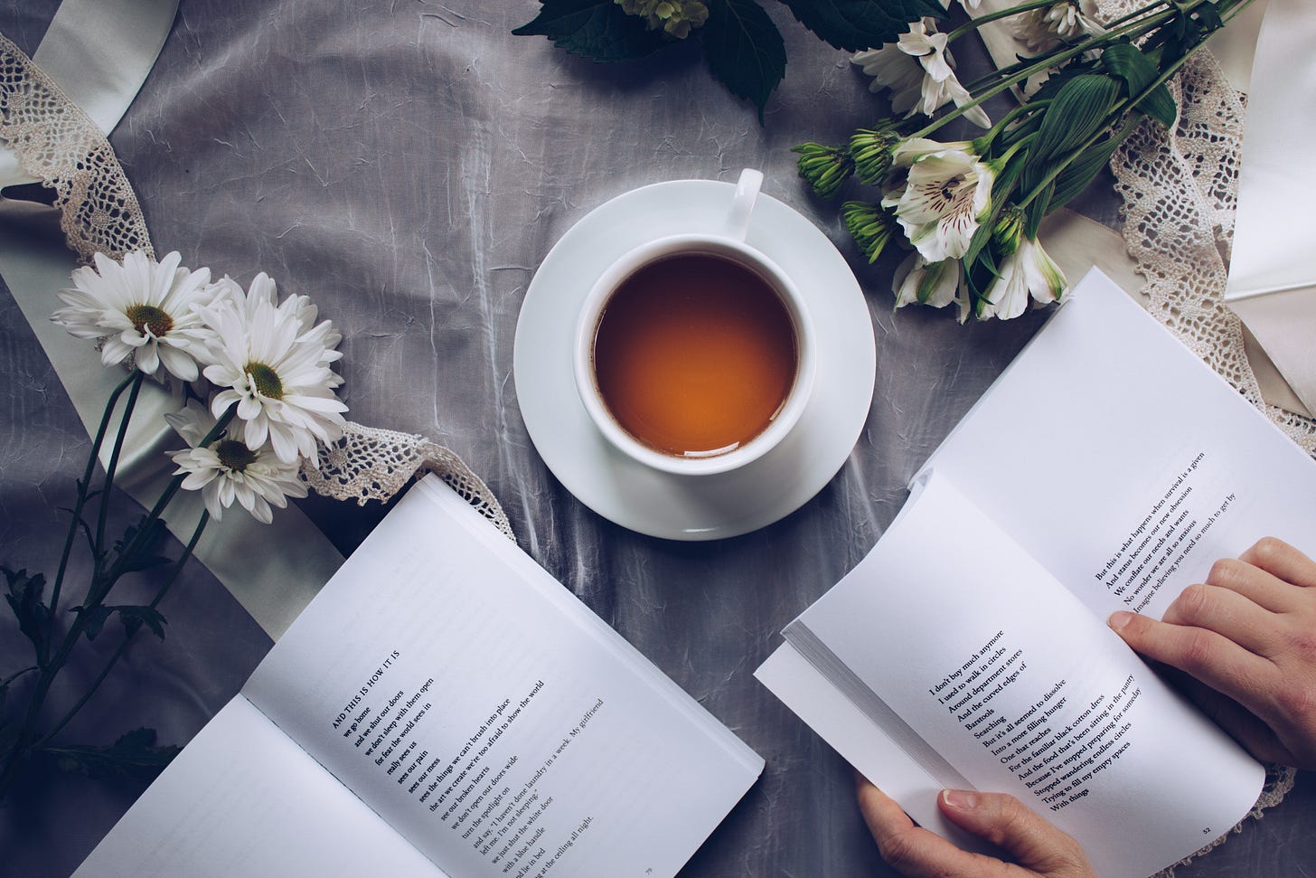 reading books next to a cup of tea, flowers and fabrics