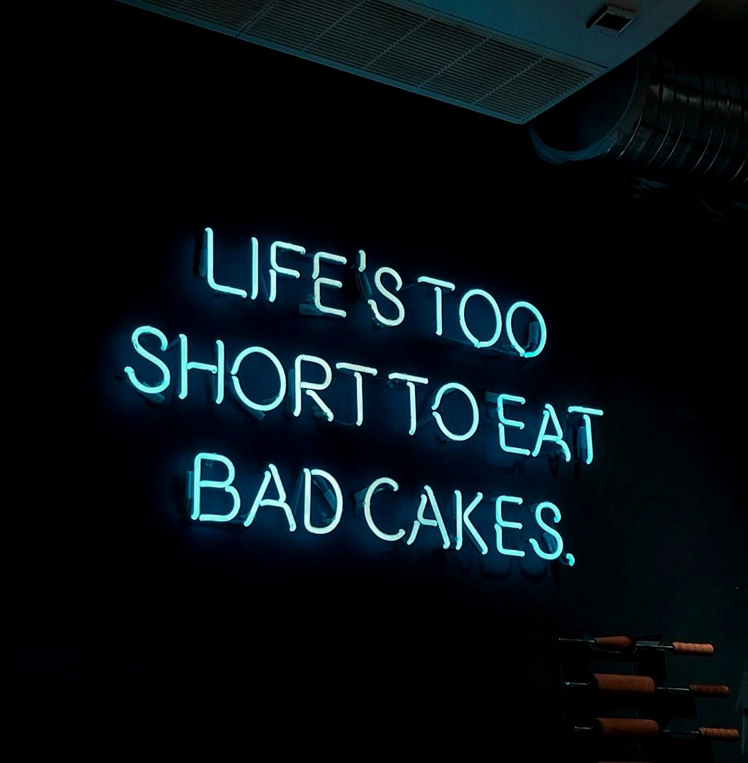A neon sign that says life's too short to eat bad cakes