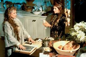A clip from Practical Magic of two older witches with long hair in a room full of flowers.