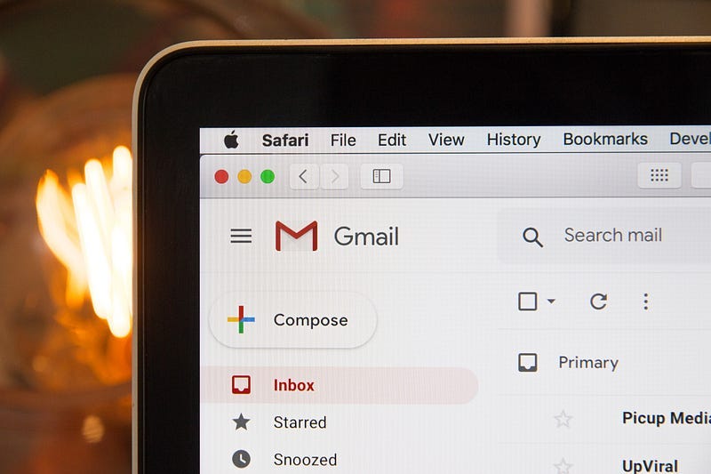 zoomed in photo of laptop with Gmail open, with blurry light bulb in the background zoomed in photo of laptop with Gmail open, with blurry light bulb in the background