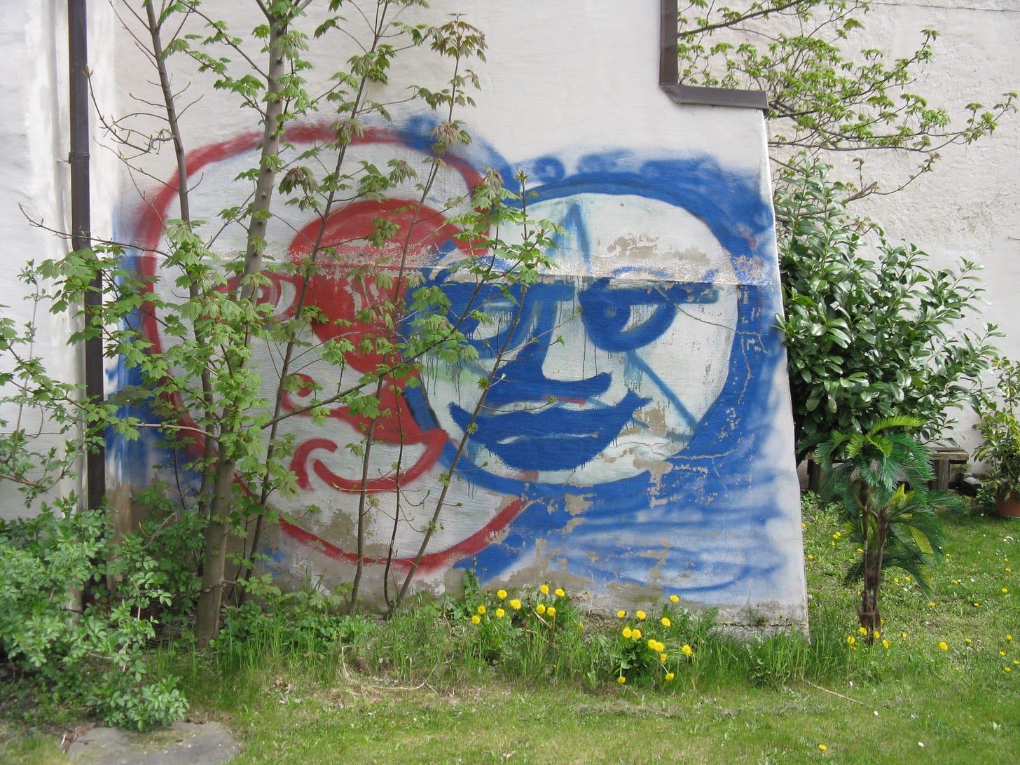 Grafitti of two cartoon sketch faces on exterior white wall
