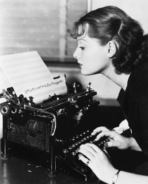 This may contain: a woman typing on an old fashioned typewriter