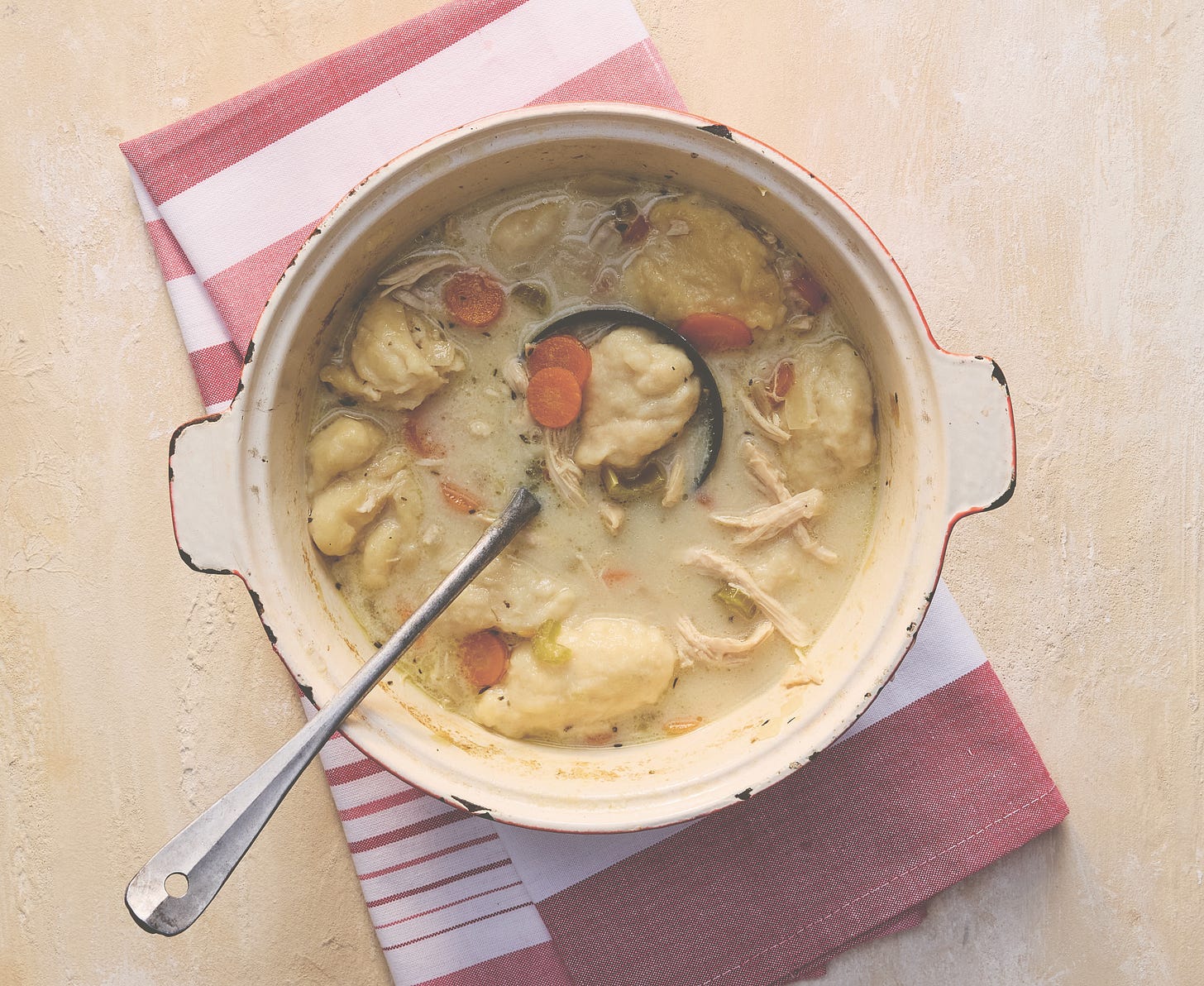 Pot of chicken and dumplings on a striped kitchen towel.