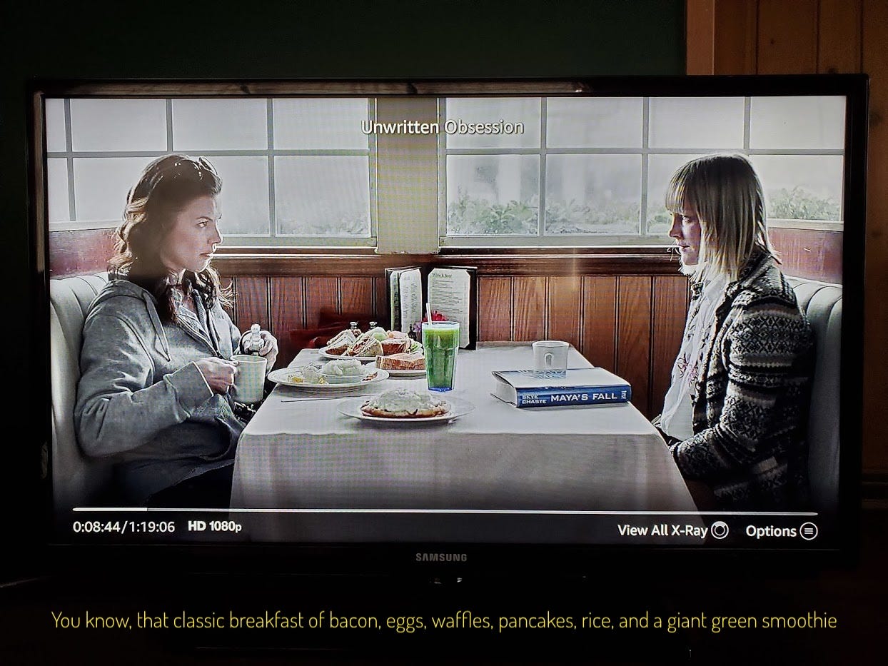 Skye and Holly at a diner table, with lots and lots of food on Skye's side of the table, captioned "You know, that classic breakfast of bacon, eggs, waffles, pancakes, rice, and a giant green smoothie"