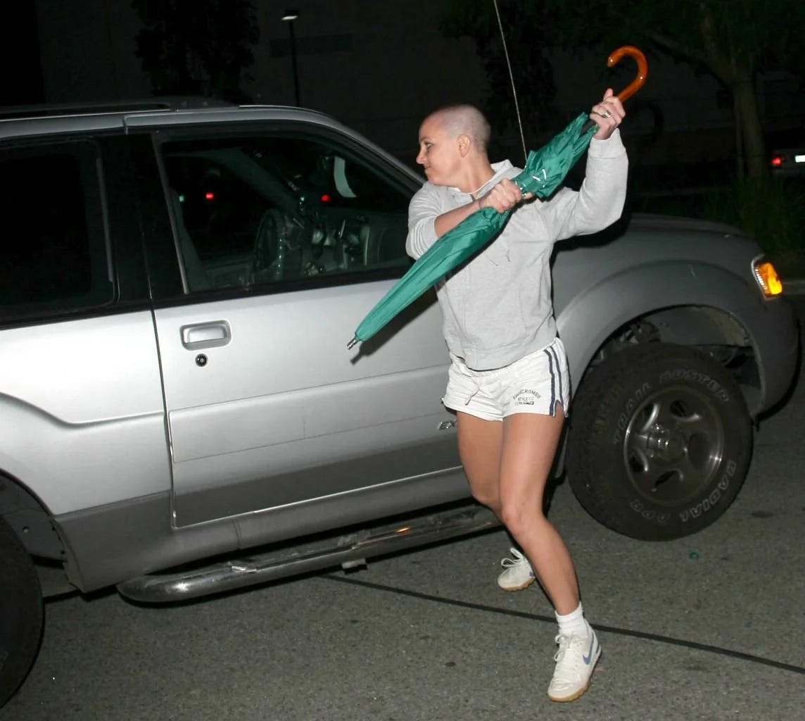 A bald headed britney spears attacking the paparazzi with an umbrella