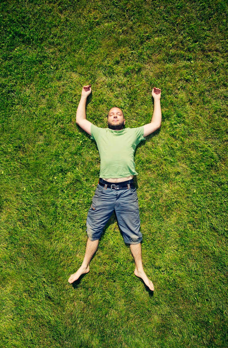 Man lying on grass in summer stock photo