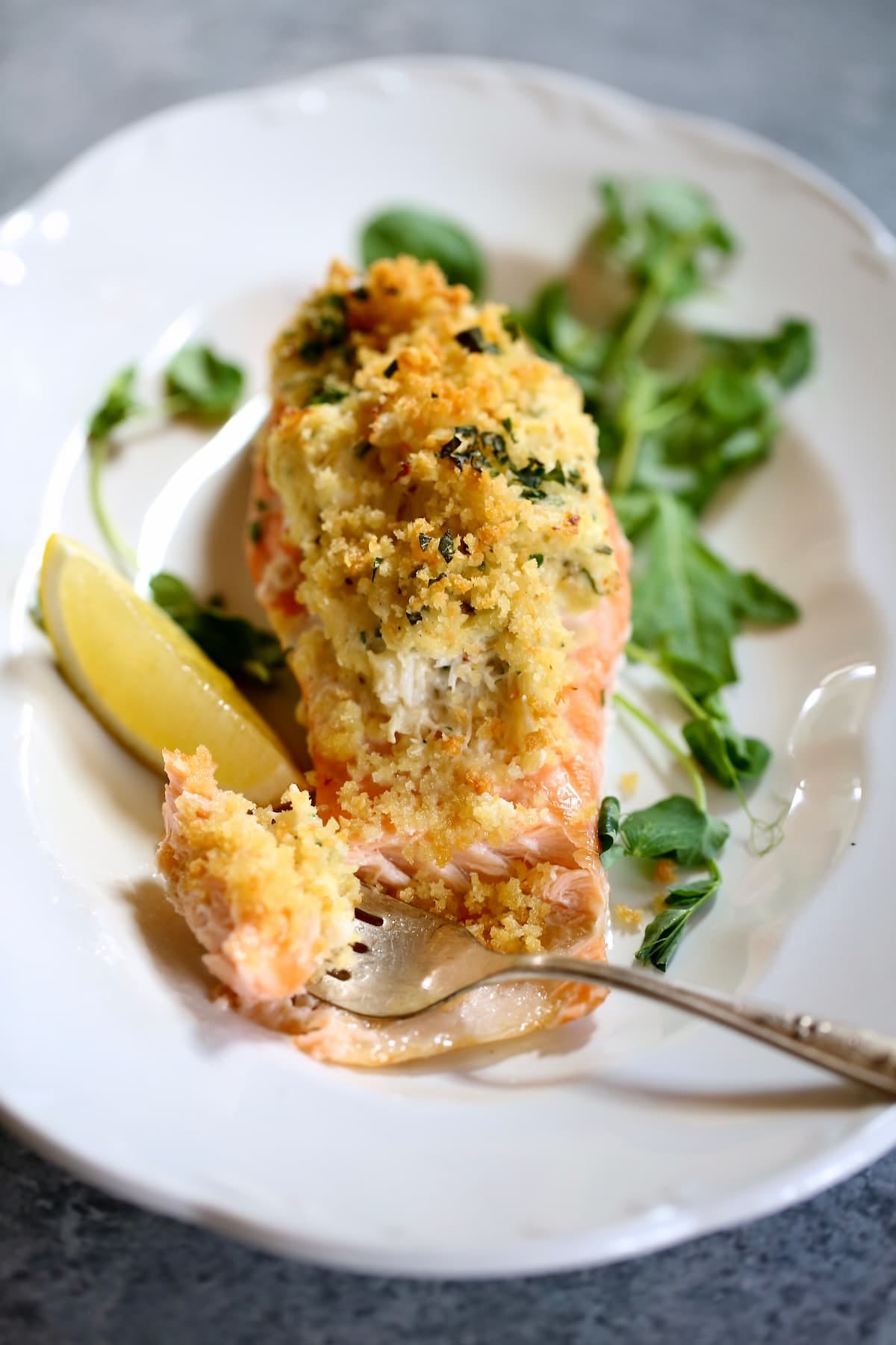 a white plate with a serving of stuffed salmon on it and a fork showing the inside.