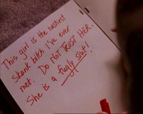 A scene from Mean Girls showing an open page of the Burn Book. Written in red marker, the text says: “This girl is the nastiest skank b*** I’ve ever met. Do NOT TRUST HER. She is a fugly slt!” The handwriting is aggressive, with parts underlined, capturing the film’s iconic moment of high school cruelty and gossip.