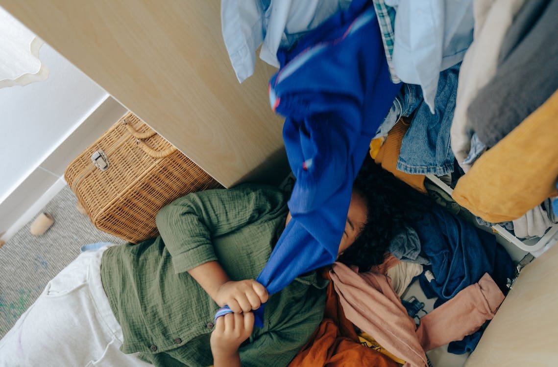 Free Anonymous black girl lying on stack of clothes in bedroom Stock Photo