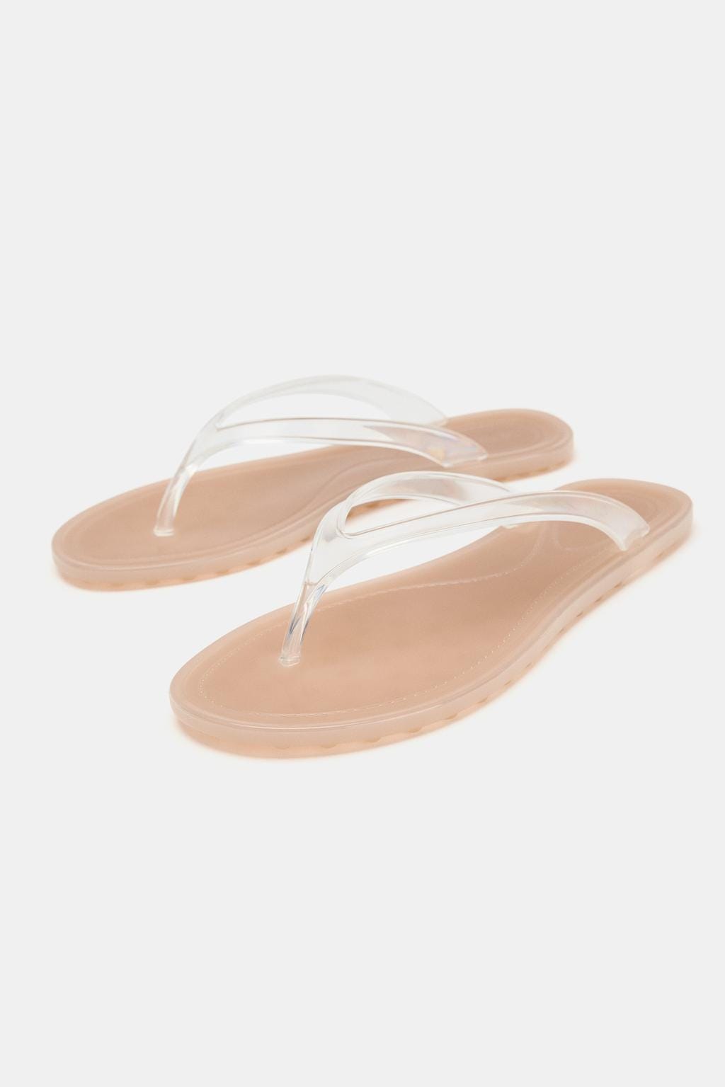 Flat sandals with a beige sole and clear straps. Flat sandals with a beige sole and clear straps.