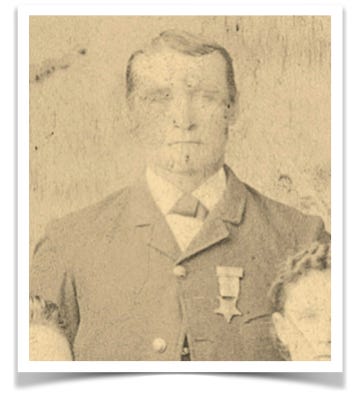 A grainy sepia-toned image of a man wearing a suit with a medal pinned on front.
