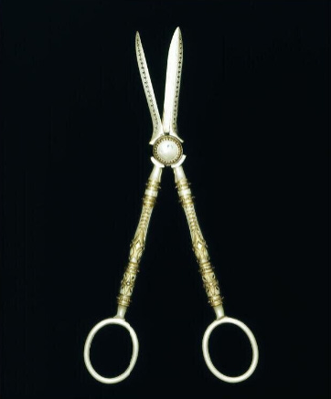 An ornate long handled pair of silver scissors for snipping grapes
