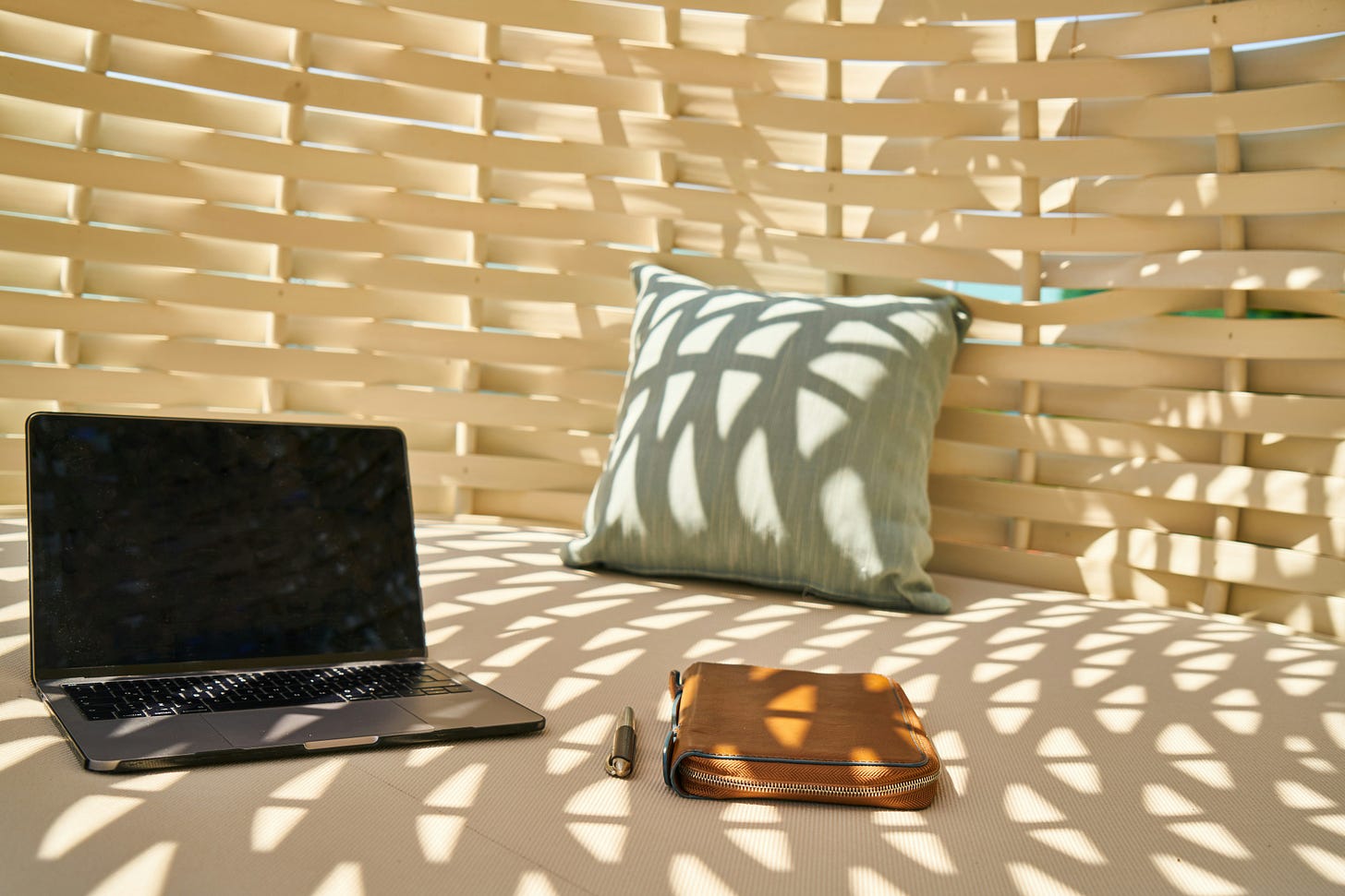 a laptop and pen in a shaded outdoor setting