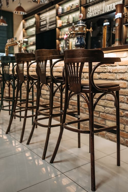 Free A cozy bar interior with wooden high stools and a brick counter, perfect for social gatherings. Stock Photo