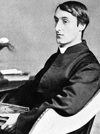 Hopkins sitting at his desk; dressed in black; turned 3/4, holding book in lap Hopkins sitting at his desk; dressed in black; turned 3/4, holding book in lap