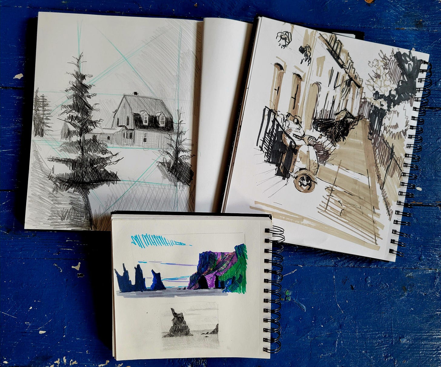 3 sketch books laying open with landscape sketches from Maine, Philadelphia, and Iceland
