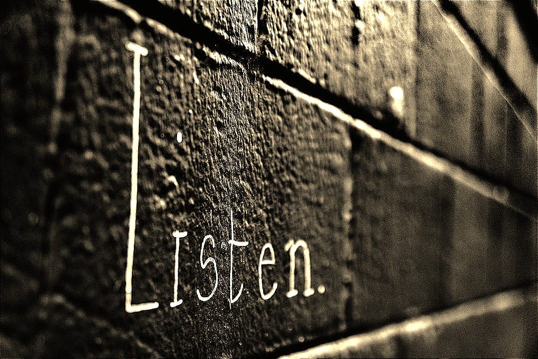 a black and white photo of the word listen written on a brick wall