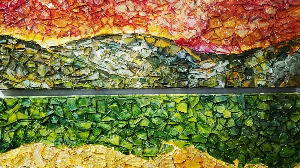 Landscape mixed media in acrylic and glass. Sunset in yellow, red and orange. Upper hills in deep green and yellow. Lower valley in bright green. Lowest valley in yellow brown. Original art by Anna Loscotoff.