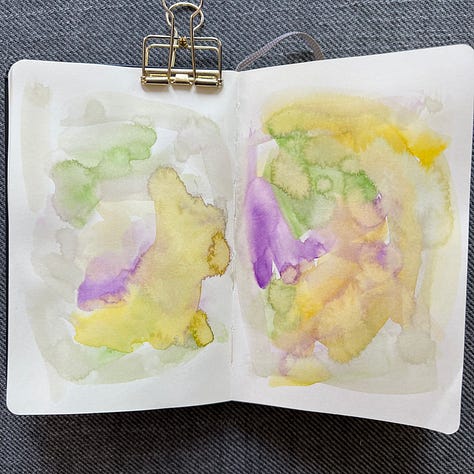 Different pages in a small sketchbook painted with light washes of watercolor in a variety colors