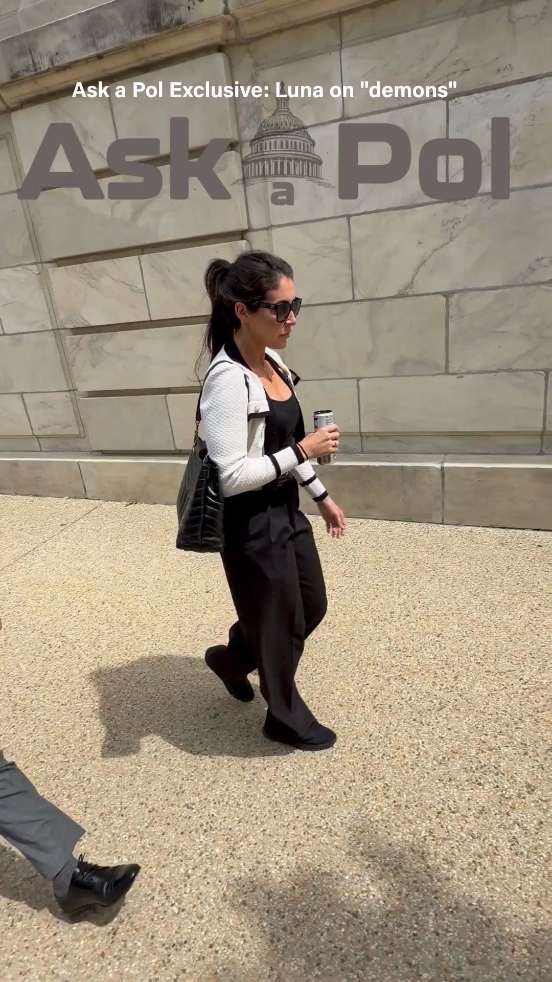 A female politician in sunglasses is holding a coffee cup and walking on a sunny day © www.askapoluaps.com 