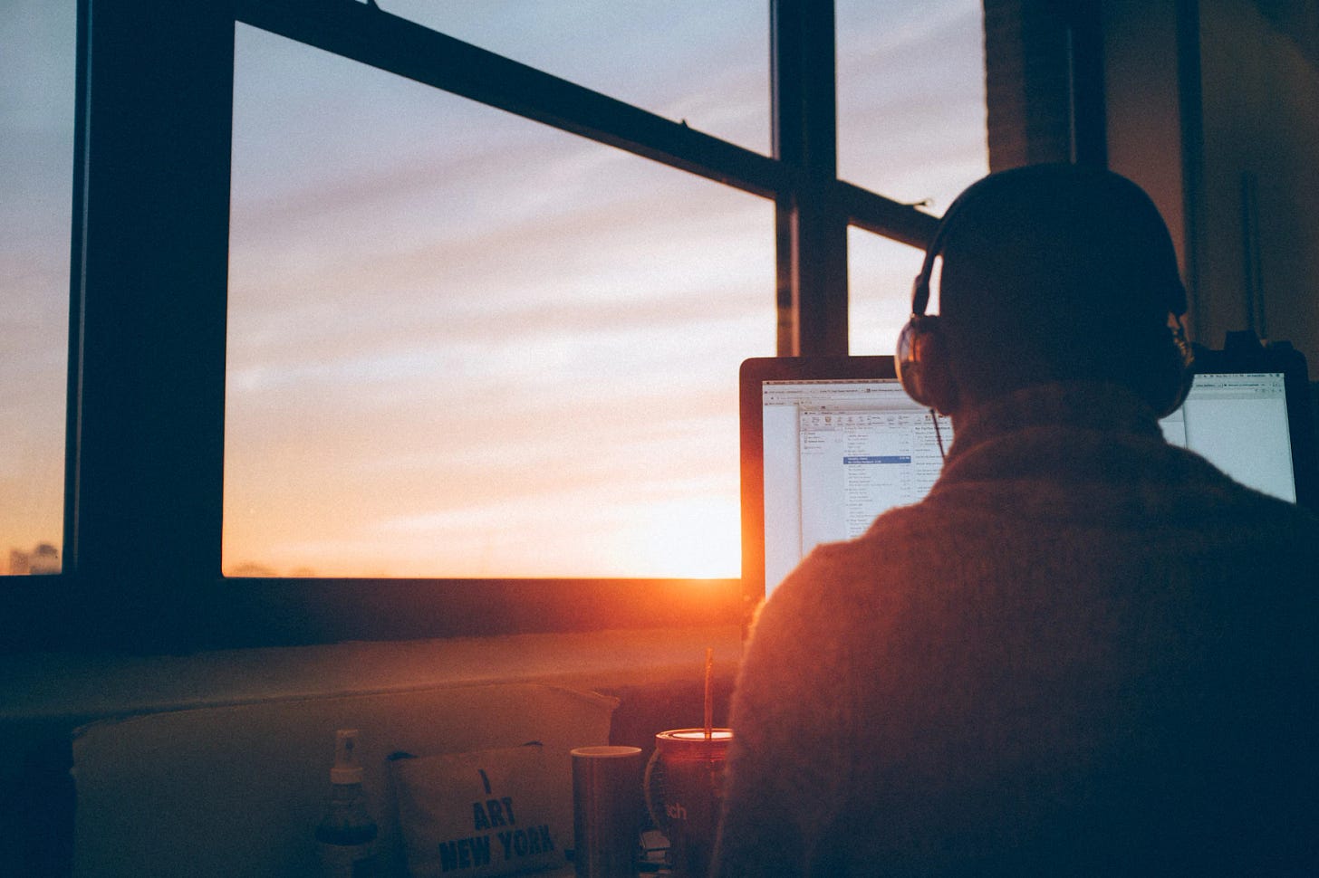 Person sitting at computer in front of window Person sitting at computer in front of window