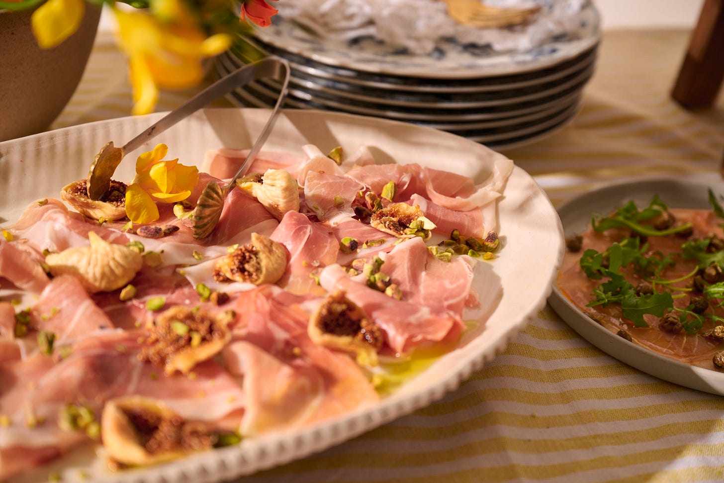 Italian antipasti platter with tuna carpaccio, prosciutto and figs, Calabrian chili butter, and crusty bread on a sunlit table Italian antipasti platter with tuna carpaccio, prosciutto and figs, Calabrian chili butter, and crusty bread on a sunlit table