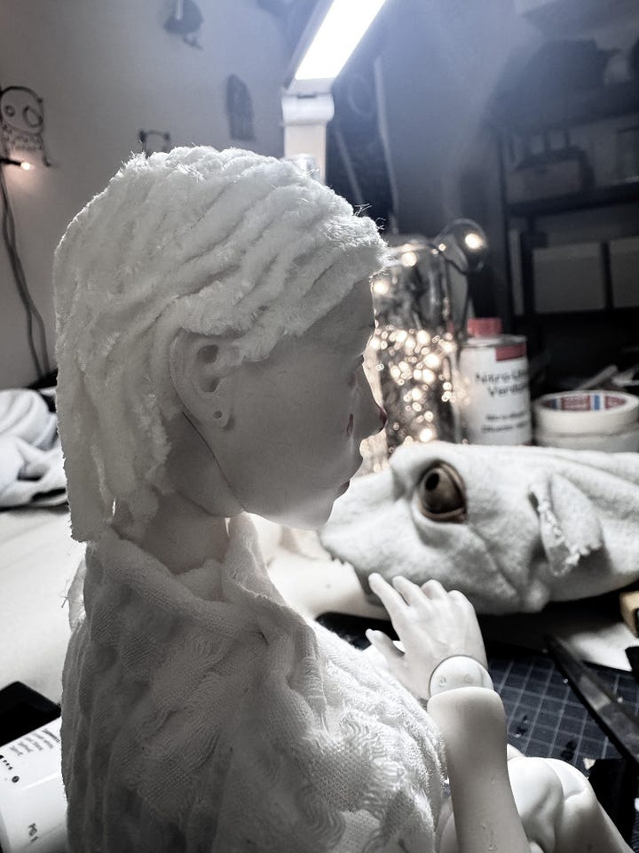 A ball jointed puppet with red dots on the cheeks and a red nose, discovering her own self