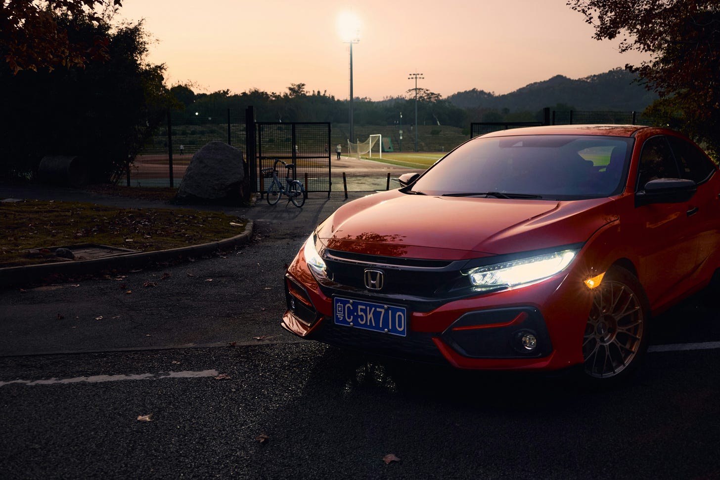 A red Honda sits outside at dusk.