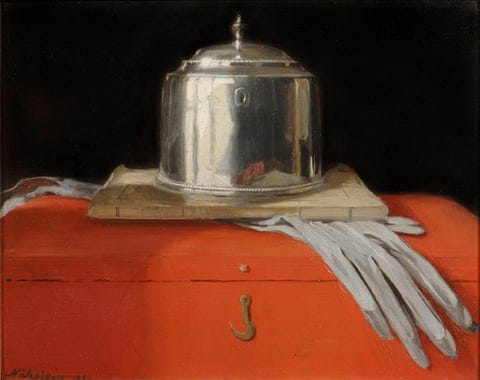 A silver cylindrical casket with a pair of grey gloves beneath it sitting on top of a red box.