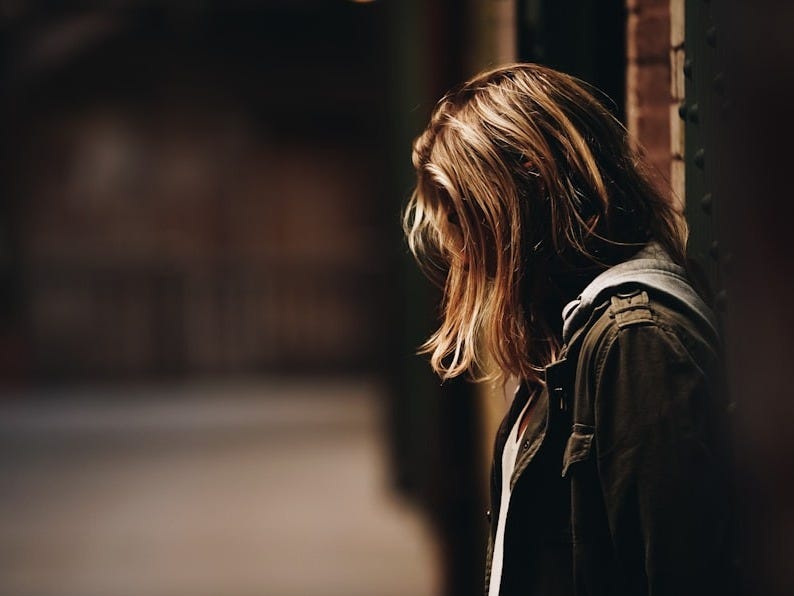 woman leaning against a wall in dim hallway