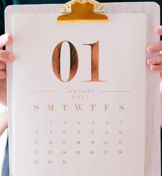 a pair of white-skinned hands hold up a clipboard to which a calendar sheet headed "O1" is clipped