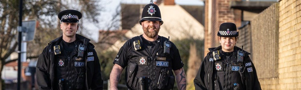 Two male officers and a female officer smiling and walking towards the camera