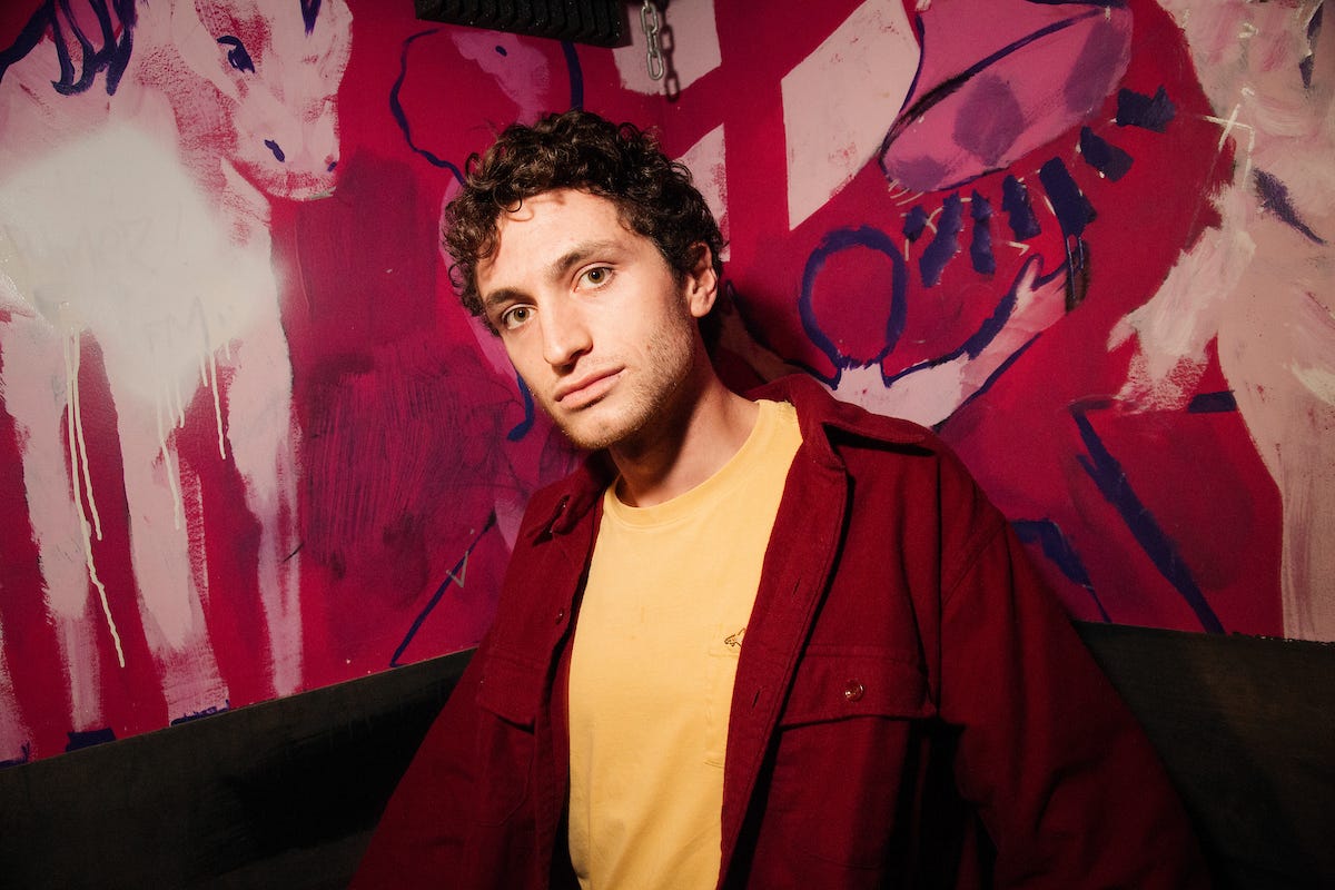Charlie Bardey standing in front of a painting of goats