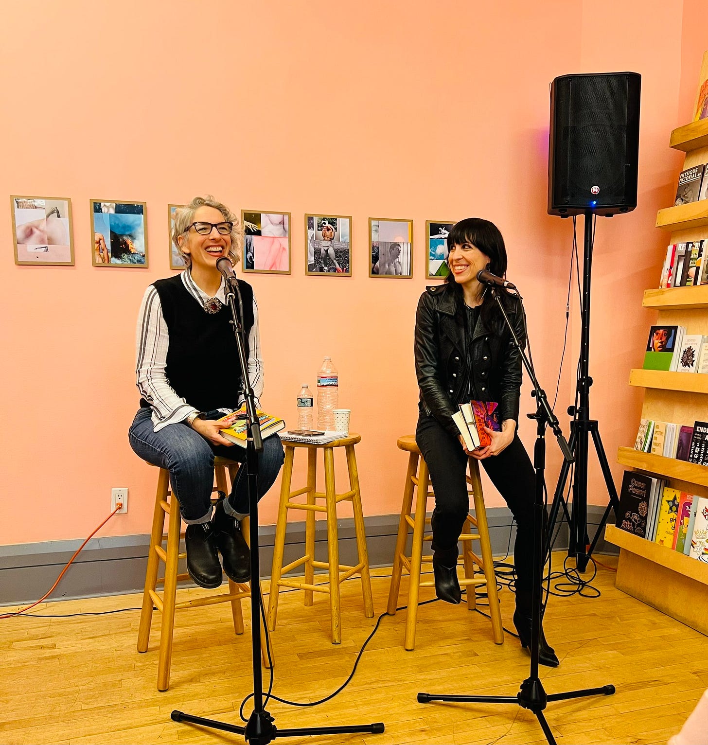 Margot Douaihy and I sit on stools in front of microphones. I'm looking ahead and smiling. Margot is looking at me and smiling.