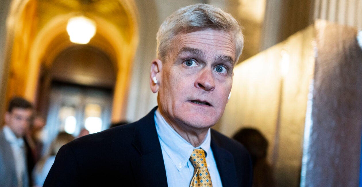 White man in suit and tie with white hair in hallway
