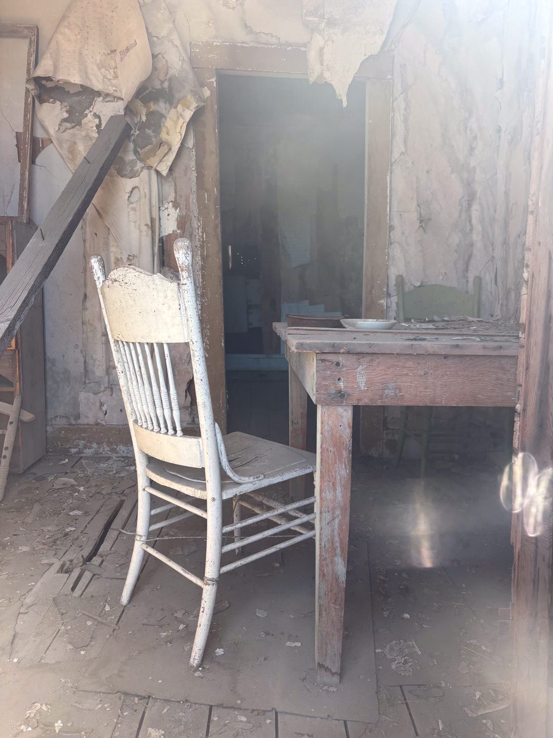 interior of a room in decaying state with peeling walls and table with chair