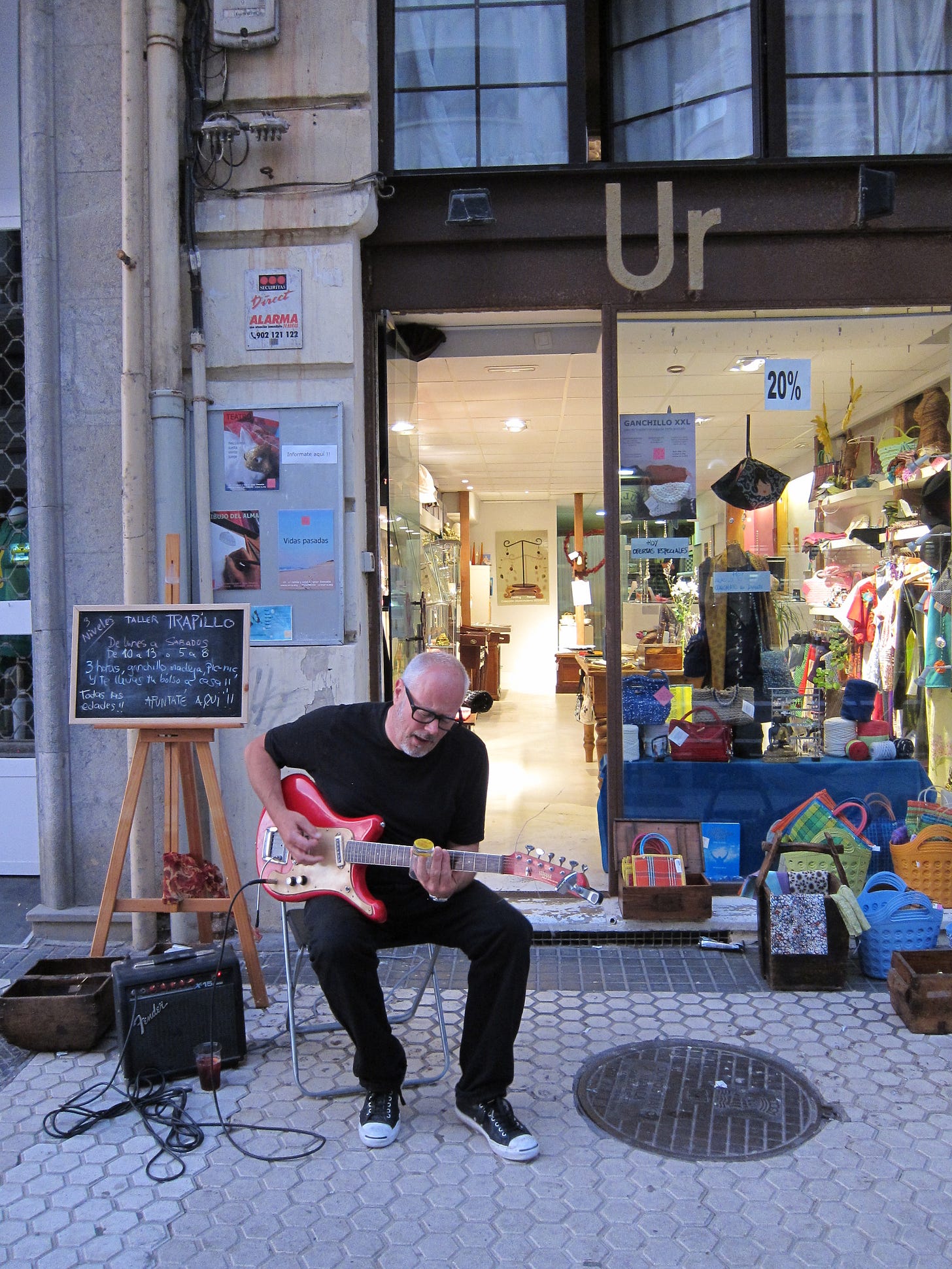 A man playing guitar outside a shop