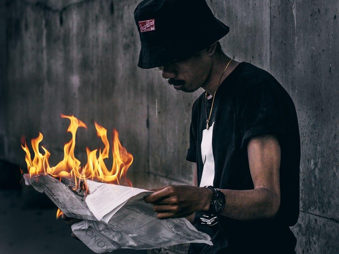 unknown person holding lit newspaper