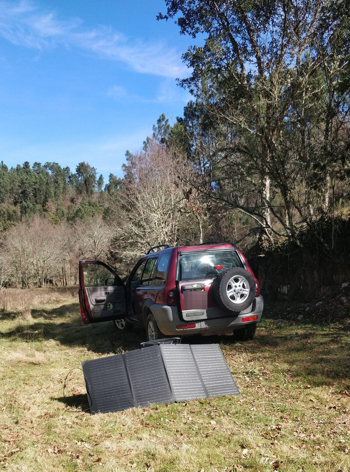 Photo of landrover standing in a field with a solar panel behind it