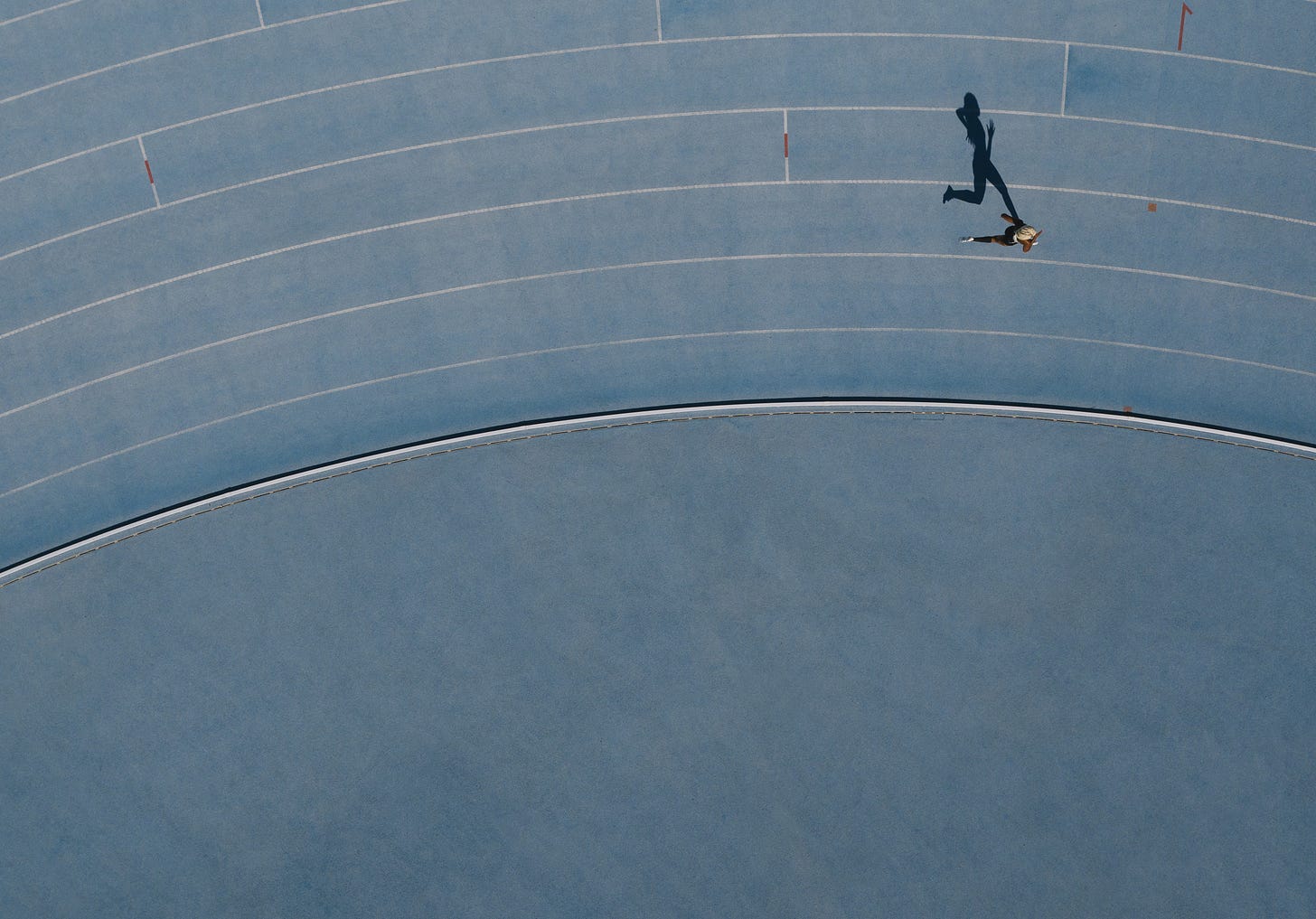 Top-down view of a track runner and their shadow Top-down view of a track runner and their shadow