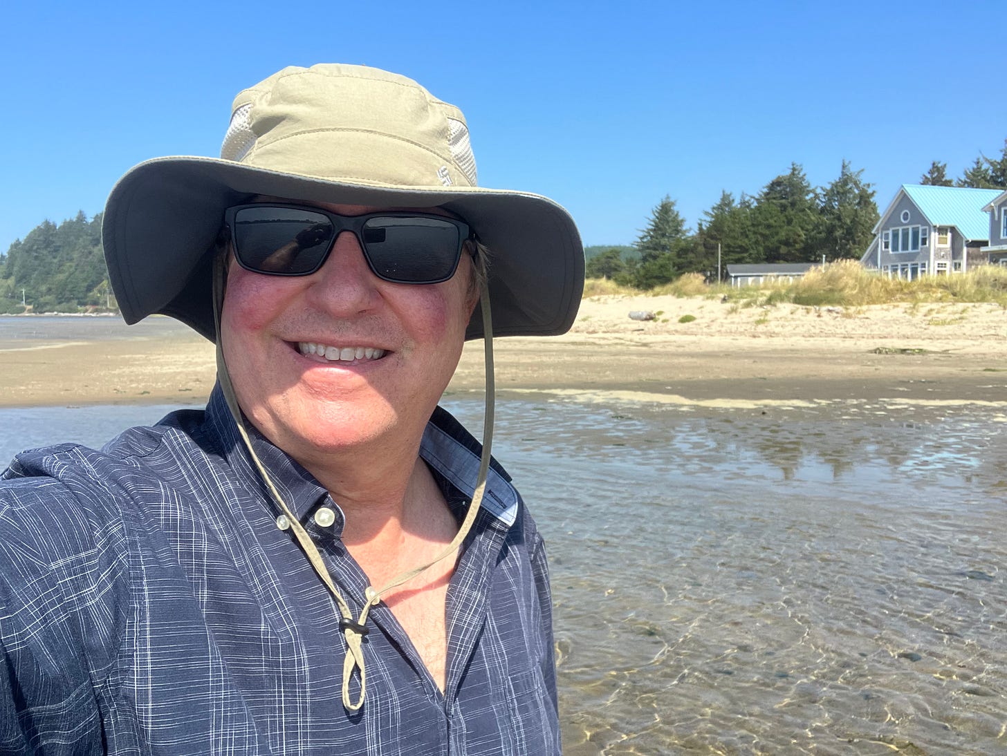 Man wearing sun glasses and sun project hat standing in water at the beach