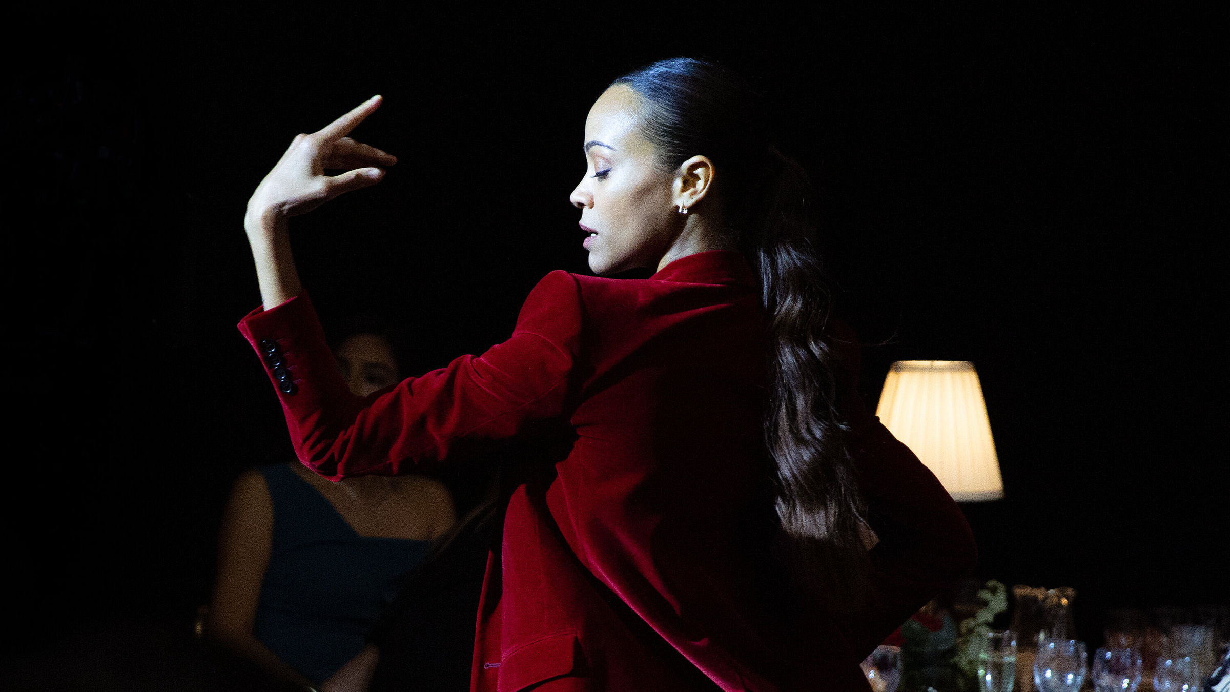 Zoe Saldana poses in a red blazer as part of a dance number in the film Emilia Pérez