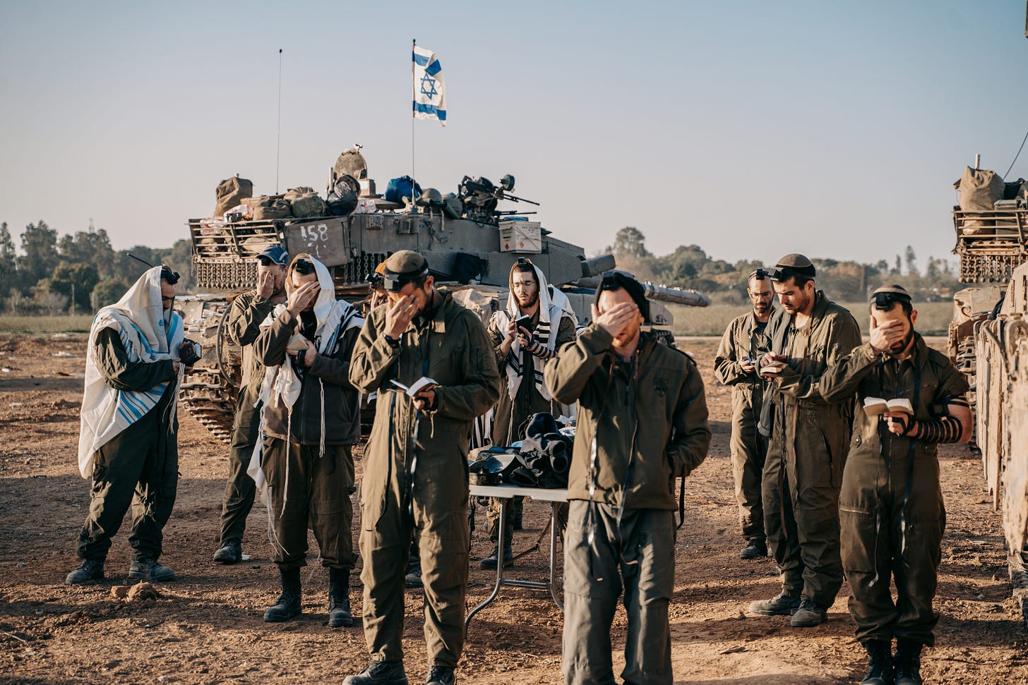 IDF soldiers putting on tefillin and tallit for morning prayer before entering Gaza IDF soldiers putting on tefillin and tallit for morning prayer before entering Gaza