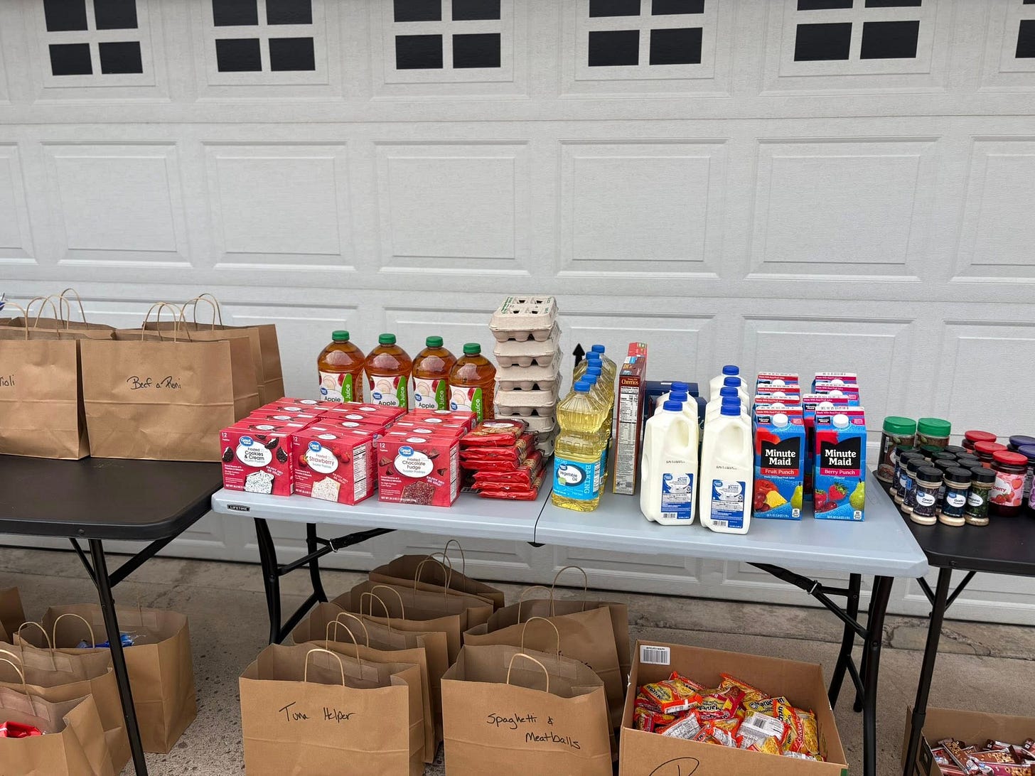 A community table set up with milk, juice, eggs, pasta, and groceries for neighbors in need — a local grab-and-go food station offering free supplies to support families during economic hardship.