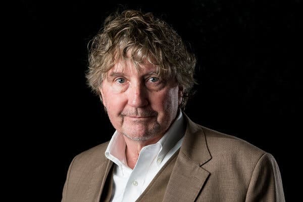 A portrait of Rod Nordland in a brown suit against a black background.
