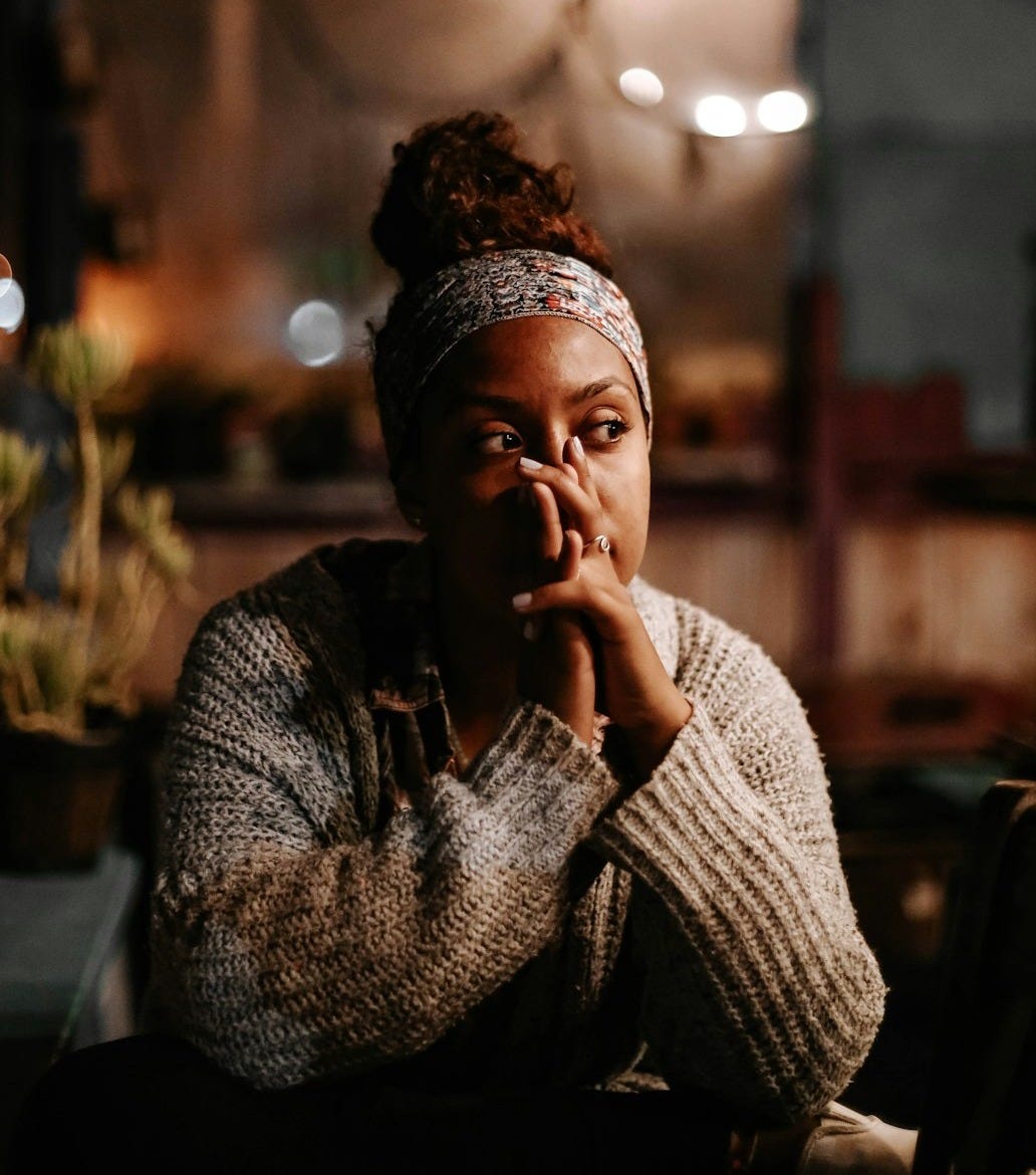 A woman with a headband and hair in a bun, hands near her face