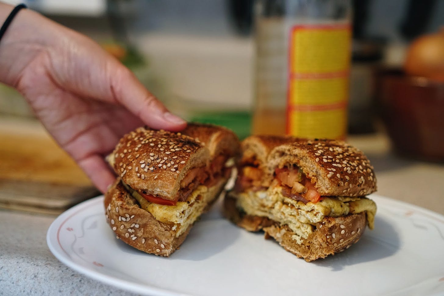 Yoko setting down a bagel egg sandwich onto a plate