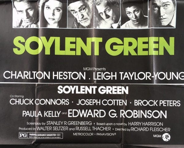 A vintage movie poster for the 1973 film Soylent Green featuring a black background with large lime-green title text reading “SOYLENT GREEN” across the center. Along the top are six black-and-white close-up portraits of cast members, including stern and serious expressions. Below the title, the names Charlton Heston and Leigh Taylor-Young appear prominently in white text, followed by supporting cast names including Chuck Connors, Joseph Cotten, Brock Peters, Paula Kelly, and Edward G. Robinson. Additional production credits and the MGM logo appear at the bottom. The poster has visible fold lines and a slightly worn texture, emphasizing its vintage theatrical style.