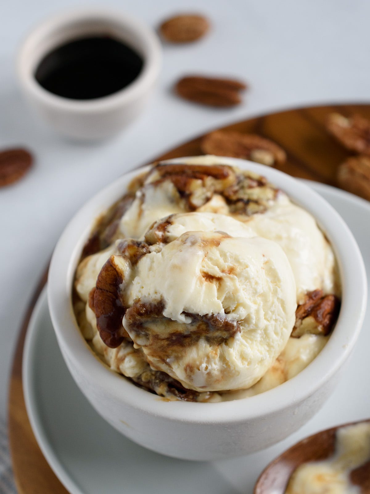 Butter pecan ice cream in white bowl with date syrup in the background. Butter pecan ice cream in white bowl with date syrup in the background.