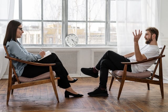 Therapist and client sitting opposite each other in rustic studio